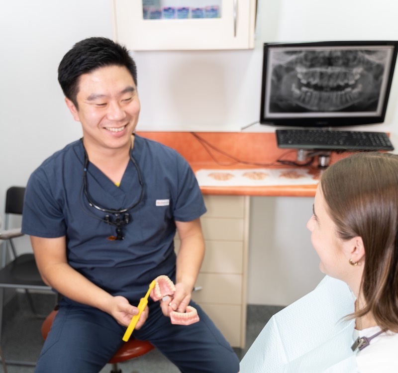 Jacky Yu teaching patient how to brush teeth to prevent decay