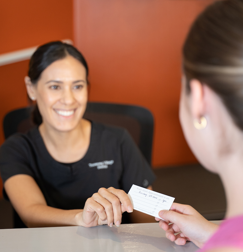 Toowong Village Dental receptionist Sam sharing new appointment card with patient